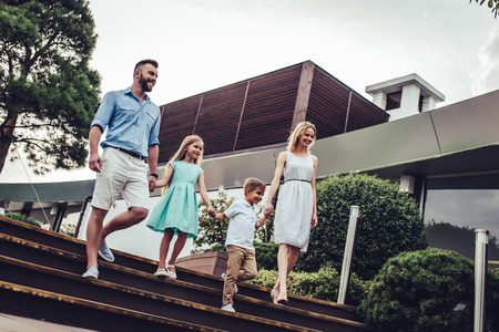 Beautiful family is spending time together  outside. Parents with their children are walking in park. Mom and dad are having fun with their charming daughter and son.の写真素材