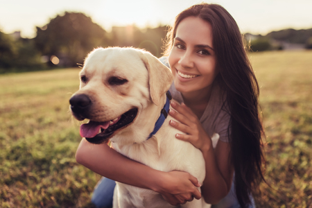 Attractive young woman with labrador outdoors. Woman on a green grass with dog labrador retriever. Smiling and looking at the camera.の写真素材