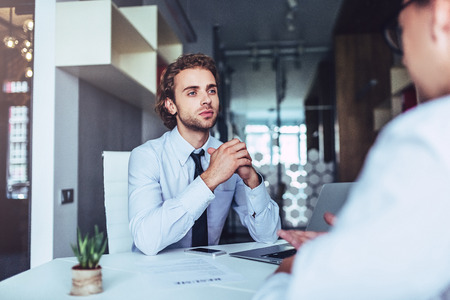 Young handsome businessman in light modern office. Job interview.の写真素材