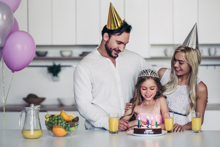 Happy family is celebrating little daughter's Birthday. Mother, father and daughter on kitchen.の写真素材