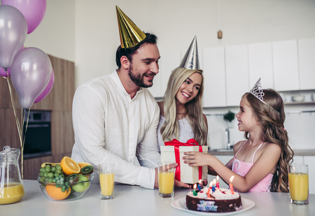 Happy family is celebrating little daughter's Birthday. Mother, father and daughter on kitchen.の写真素材