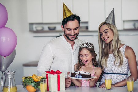 Happy family is celebrating little daughter's Birthday. Mother, father and daughter on kitchen.の写真素材