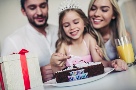 Happy family is celebrating little daughter's Birthday. Mother, father and daughter on kitchen.の写真素材