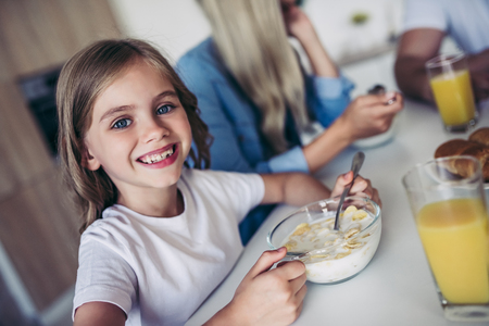 Cropped image of happy family on kitchen. Mother, father and daughter are having breakfast.の写真素材