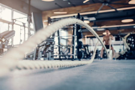 Handsome muscular man is training in gym. Sports man with rope during functional training. Crossfit.の写真素材