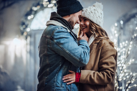 Young romantic couple is having fun outdoors in winter before Christmas. Enjoying spending time together in New Year Eve. Two lovers are hugging and kissing in Saint Valentine's Day.の写真素材