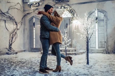 Young romantic couple is having fun outdoors in winter before Christmas. Enjoying spending time together in New Year Eve. Two lovers are hugging and kissing in Saint Valentine's Day.の写真素材