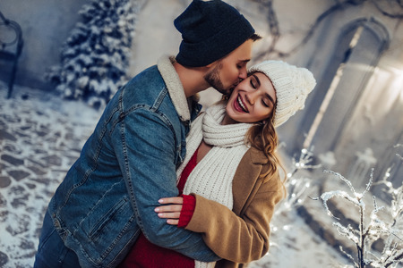 Young romantic couple is having fun outdoors in winter before Christmas. Enjoying spending time together in New Year Eve. Two lovers are hugging and kissing in Saint Valentine's Day.の写真素材