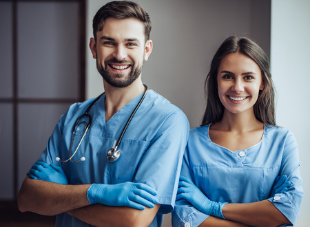 Handsome doctor veterinarian and his attractive assistant at vet clinic. Standing with hands crossed, smiling and looking at camera.の写真素材