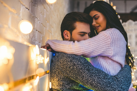 Passionate romantic couple spending time before New Year near beautiful Christmas tree at homeの写真素材