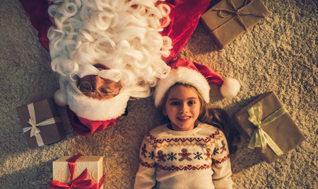 Top view of cute little girl and Santa Claus are lying on the floor with gift boxes nearby. Waiting for Christmas together. New Year Eveの写真素材
