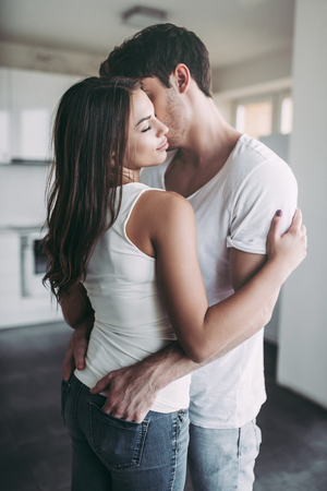 Romantic couple at home. Attractive young woman and handsome man are enjoying spending time together.の写真素材