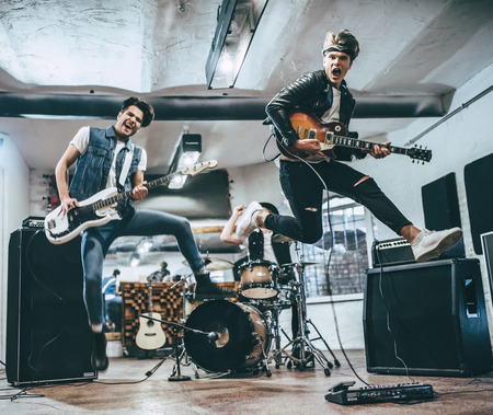 Repetition of rock music band. Bass guitar player, electro guitar player and drummer behind the drum set. Rehearsal baseの写真素材