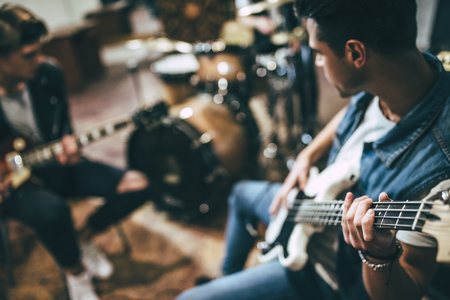 Repetition of rock music band. Bass guitar player, electro guitar player and drummer behind the drum...