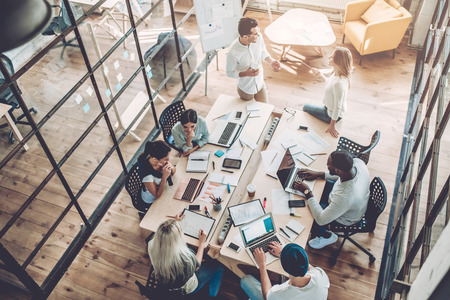 Top view of multiracial young creative people in modern office. Group of young business people are working together with laptop, tablet, smart phone, notebook. Successful hipster team in coworking. Freelancers.の写真素材