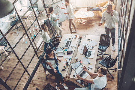 Top view of multiracial young creative people in modern office. Group of young business people are working together with laptop, tablet, smart phone, notebook. Successful hipster team in coworking. Freelancers.の写真素材
