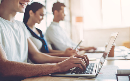 Cropped image of multiracial young creative people in modern office. Group of young business people are working together with laptop, tablet, smart phone, notebook. Successful hipster team in coworking. Freelancers.の写真素材