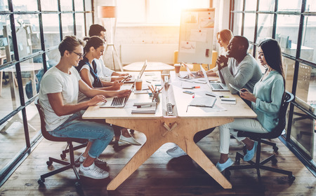 Multiracial young creative people in modern office. Group of young business people are working together with laptop, tablet, smart phone, notebook. Successful hipster team in coworking. Freelancers.の写真素材