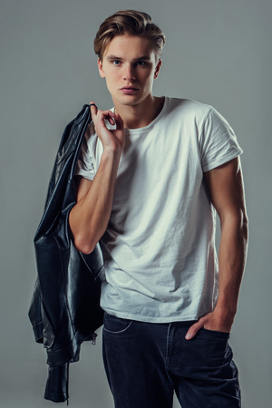 Handsome young man isolated. Fashionable  man with leather jacket is standing on grey background.の写真素材