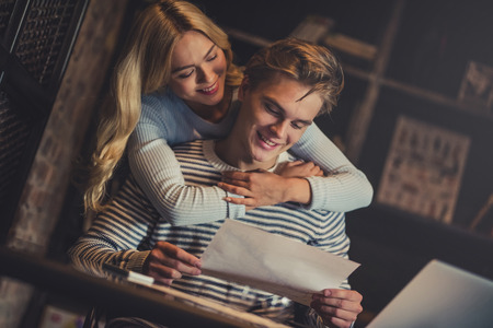 Handsome young man and attractive young woman are hugging while spending time together. Romantic couple is working in cafe.の写真素材