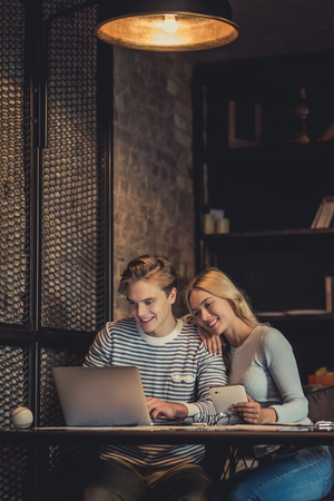 Handsome young man and attractive young woman are spending time together. Romantic couple is working in cafe with laptop and tablet.の写真素材