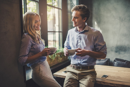 Handsome young man and attractive young woman are spending time together. Romantic couple in cafe is drinking coffee and enjoying being together.の写真素材