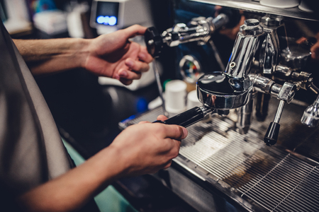 Male barista is working in cafe. Cropped image of handsome man making coffee.の写真素材