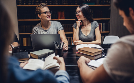 Students are studying in library. Young people are spending time together. Young handsome men and attractive women are working together.の写真素材