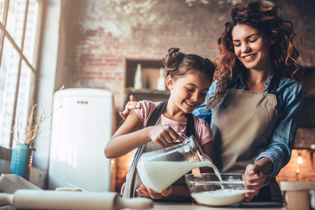 Attractive young woman and her little cute daughter are cooking on kitchen. Having fun together while making cakes and cookies.の写真素材
