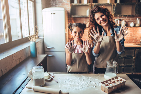 Attractive young woman and her little cute daughter are cooking on kitchen. Having fun together while making cakes and cookies.の写真素材