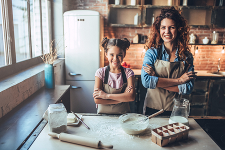 Attractive young woman and her little cute daughter are cooking on kitchen. Having fun together while making cakes and cookies.の写真素材