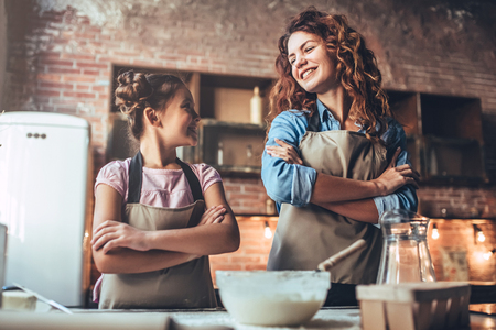 Attractive young woman and her little cute daughter are cooking on kitchen. Having fun together while making cakes and cookies.の写真素材