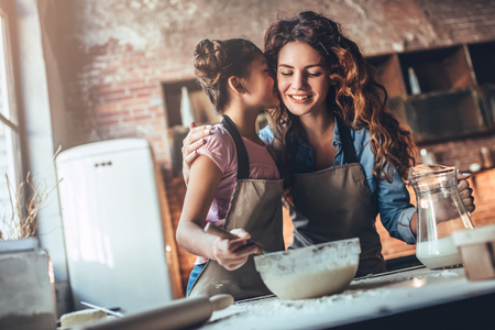 Attractive young woman and her little cute daughter are cooking on kitchen. Having fun together while making cakes and cookies.の写真素材