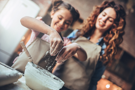 Attractive young woman and her little cute daughter are cooking on kitchen. Having fun together while making cakes and cookies.の写真素材