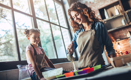 Attractive young woman and her little cute daughter are cooking on kitchen. Having fun together while making cakes and cookies.の写真素材