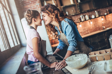 Attractive young woman and her little cute daughter are cooking on kitchen. Having fun together while making cakes and cookies.の写真素材