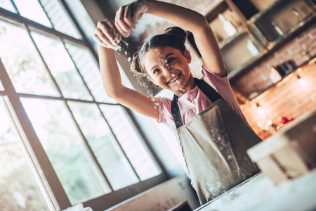 Little cute girl is cooking on kitchen. Having fun while making cakes and cookies.の写真素材