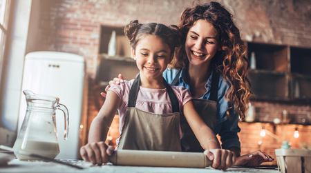 Attractive young woman and her little cute daughter are cooking on kitchen. Having fun together while making cakes and cookies.の写真素材
