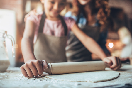 Cropped image of attractive young woman and her little cute daughter are cooking on kitchen. Having fun together while making cakes and cookies.の写真素材