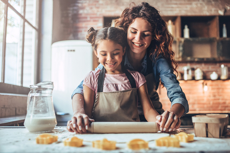 Attractive young woman and her little cute daughter are cooking on kitchen. Having fun together while making cakes and cookies.の写真素材