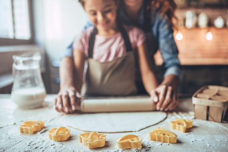 Cropped image of attractive young woman and her little cute daughter are cooking on kitchen. Having fun together while making cakes and cookies.の写真素材