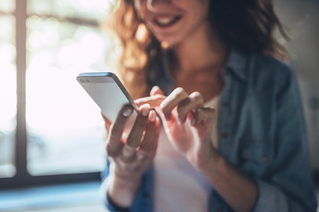 Cropped image of attractive young curly woman with smart phone.の写真素材