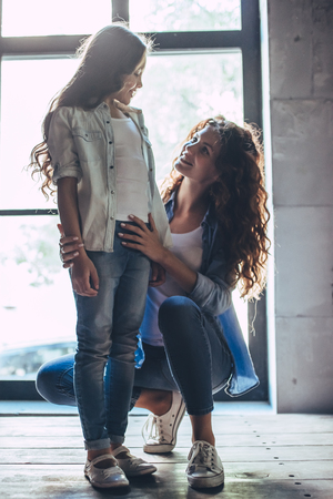 Beautiful curly woman and her little pretty daughter at home. Having fun and enjoying being together.の写真素材