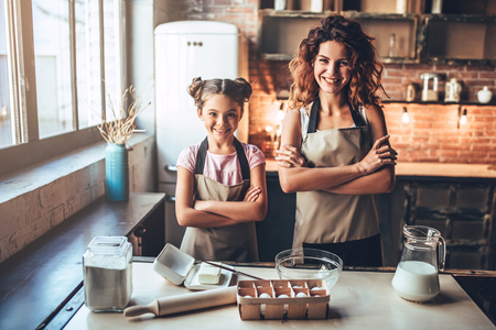 Attractive young woman and her little cute daughter are cooking on kitchen. Having fun together while making cakes and cookies.の写真素材