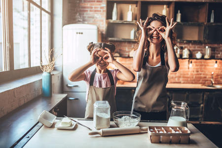 Attractive young woman and her little cute daughter are cooking on kitchen. Having fun together while making cakes and cookies.の写真素材