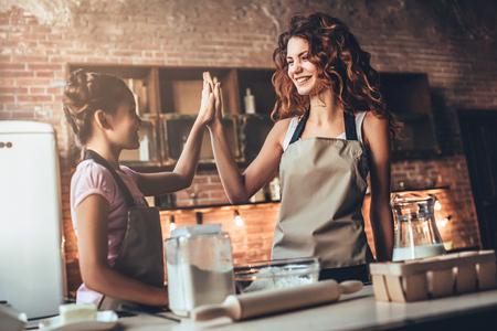 Attractive young woman and her little cute daughter are cooking on kitchen. Having fun together while making cakes and cookies.の写真素材