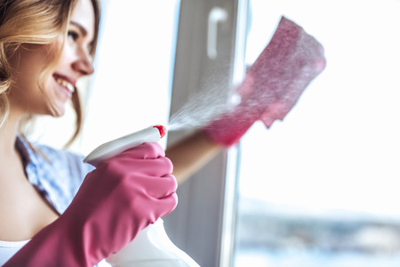 Attractive young woman is washing windows while doing cleaning at home.の写真素材
