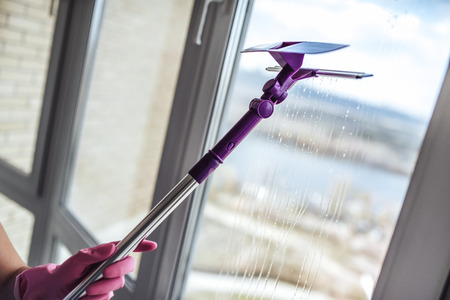 Attractive young woman is washing windows while doing cleaning at home.の写真素材