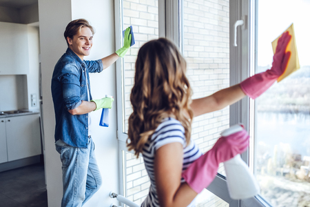 Young happy couple is washing windows while doing cleaning at home.の写真素材