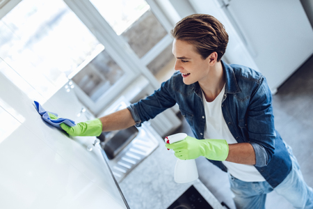 Handsome young man is washing kitchen while doing cleaning at home.の写真素材